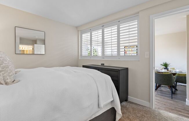 a bedroom with a large window and a door leading to a dining room