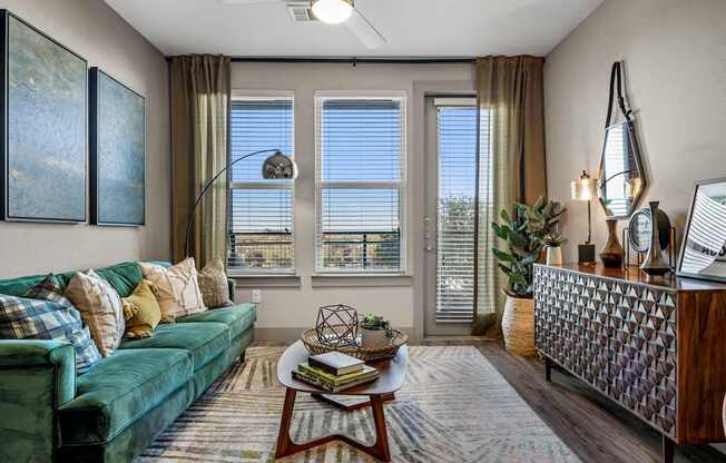 A living room with a green couch, a coffee table, and a large window.