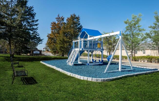 a playground with a swing set and a blue playset