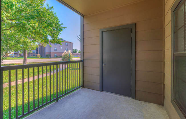 Pet-Friendly Apartments in Spring, TX - Spacious Patio with Metal Railing, a Storage Room and a View of Grass and Trees.