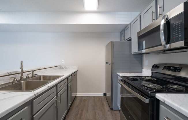 an empty kitchen with stainless steel appliances and white counter tops