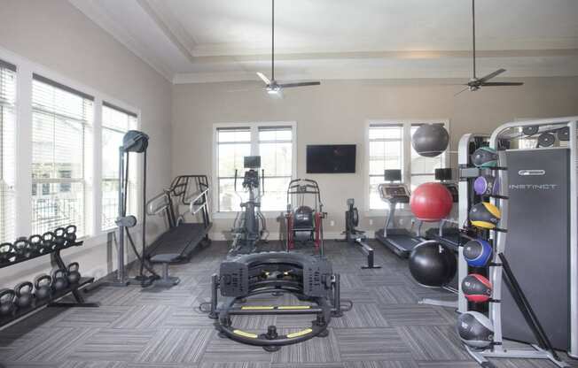 a home gym with a lot of equipment and windows