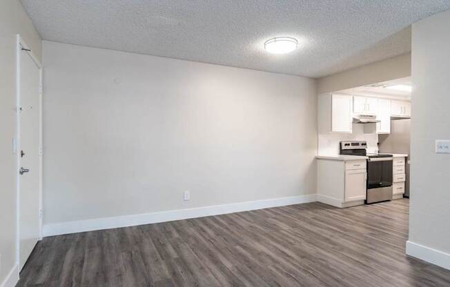 A room with a wooden floor and a white wall with a door on the left side.