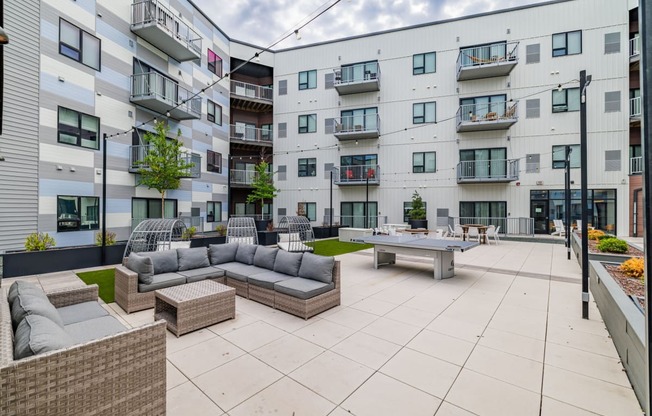 an open courtyard with couches and tables in front of an apartment building