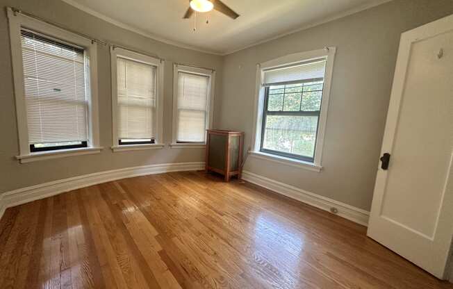 an empty living room with wood floors and a ceiling fan