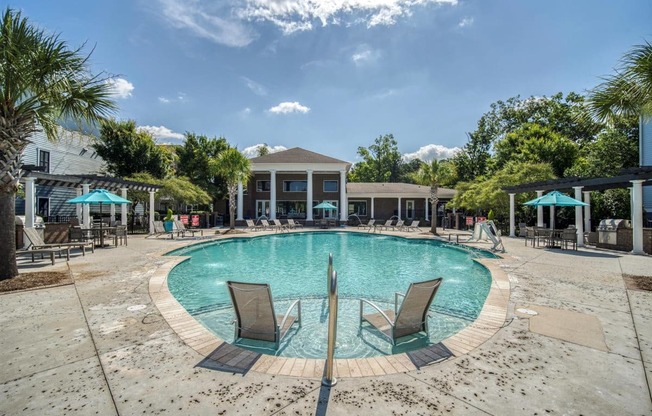 A large swimming pool surrounded by lounge chairs and umbrellas.