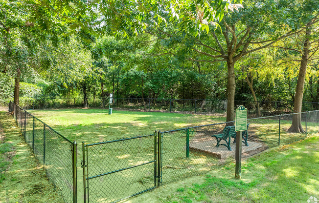 A green sign is in front of a fence and a tree.