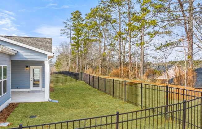the front yard of a house with a fence and a yard with trees
