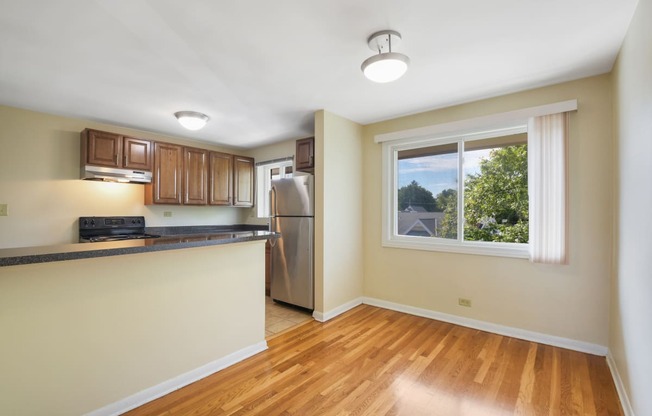 an empty kitchen with a window and a stainless steel refrigerator