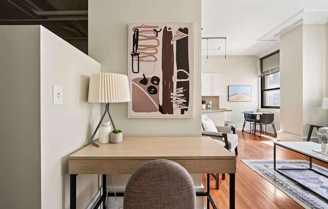 A modern home office with a desk, chair, and a large abstract painting on the wall.
