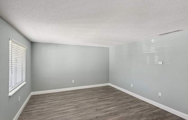 A room with wooden flooring and a window with blinds.