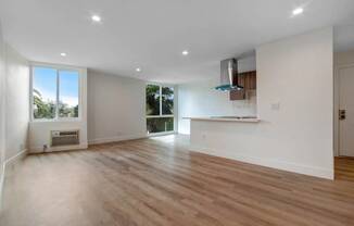 an empty living room with a kitchen and a large window