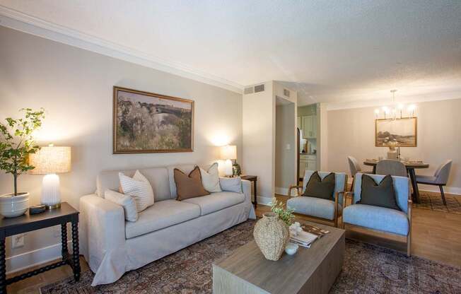 A living room with a couch, chairs, and a painting on the wall.