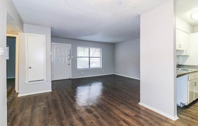 an empty living room and kitchen with wood flooring