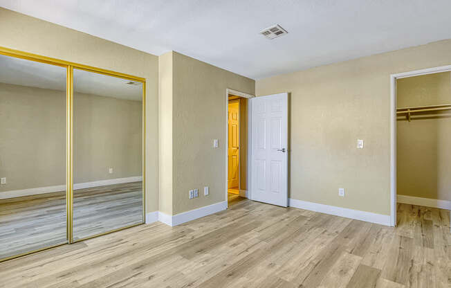 the living room of an empty apartment with wood floors and a door to the hallway
