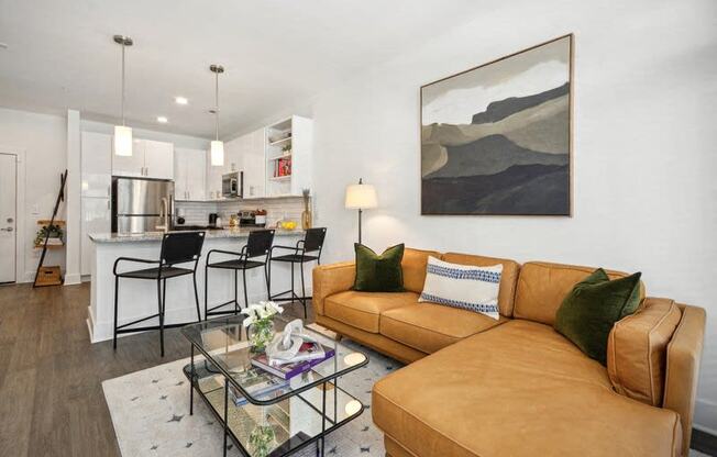 a living room and kitchen with a couch and a glass table at Link Apartments® 4th Street, North Carolina