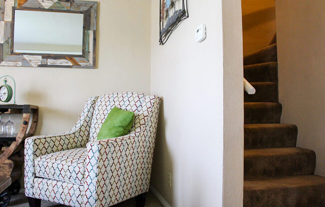 a chair with a green pillow in a room with a staircase