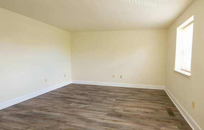 an empty room with a window and a wooden floor