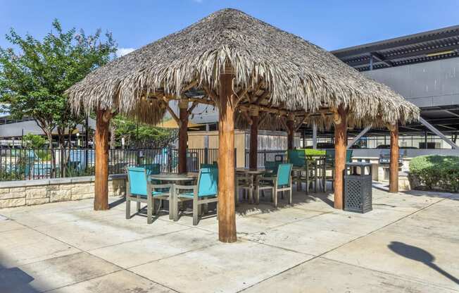 a patio with a thatched umbrella and tables and chairs