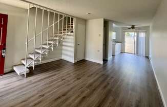 an empty living room with a staircase and hard wood floors