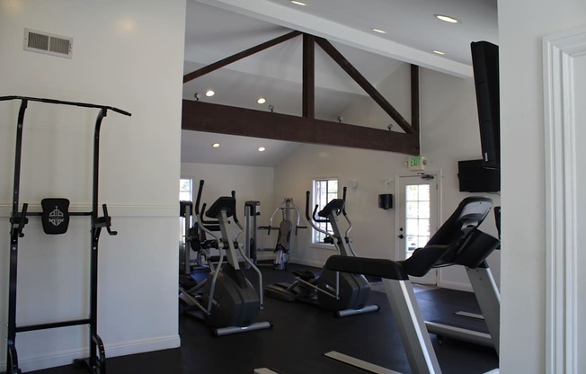 A gym with a variety of equipment including a treadmill, a stationary bike and a rowing machine.