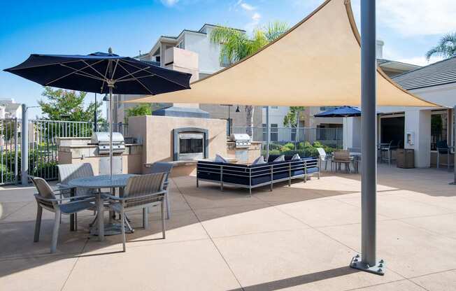 A patio with a table and chairs under a blue and a beige umbrella.