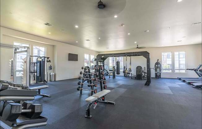 A spacious gym with a variety of equipment including dumbbells, weight machines, and a bench press at Northplace Apartment Homes, Salem, Oregon