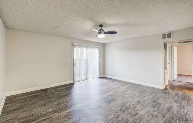 an empty living room with wood flooring and a ceiling fan