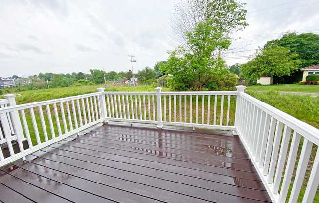 A wooden deck with white railings and a wet surface.
