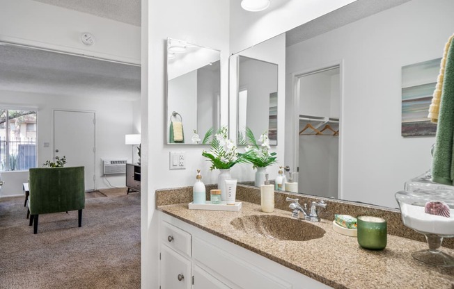a bathroom with a sink and mirrors and a living room