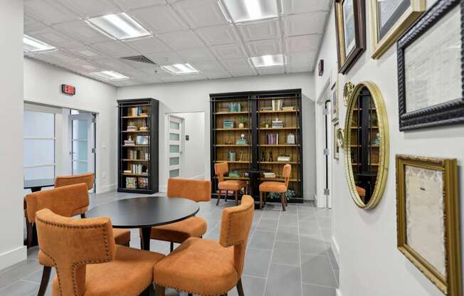 A room with a table surrounded by chairs and bookshelves.