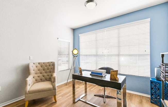 a living room with a chair and a glass desk