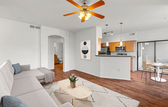 A living room with a grey couch and a ceiling fan.