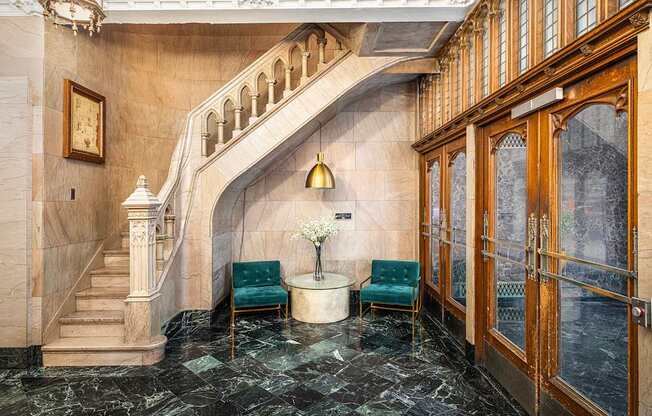 A marble staircase with a green chair and a table with a vase of flowers.
