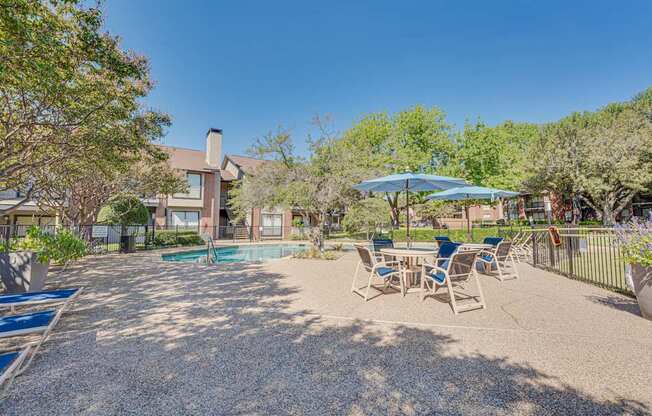 A backyard with a pool, patio furniture, and trees.