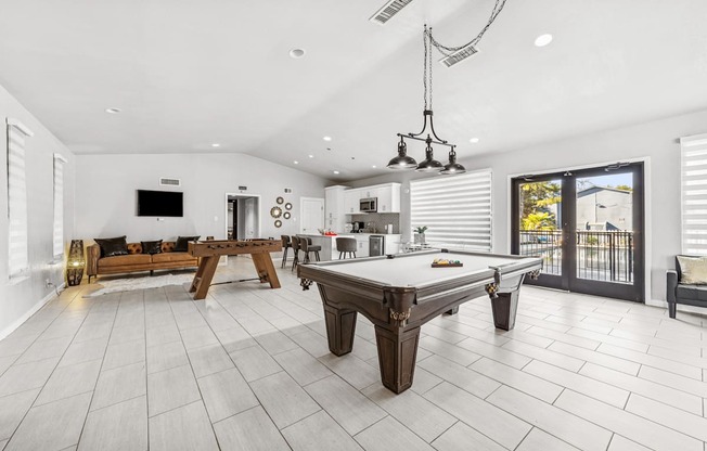 A billiard table is in the middle of a white tiled room.