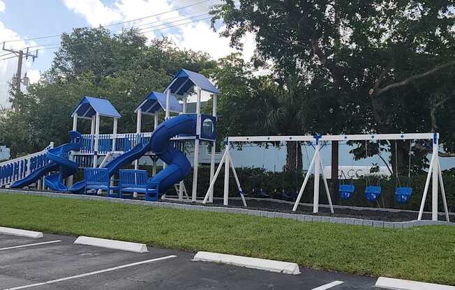 a playground with a blue slide in a parking lot