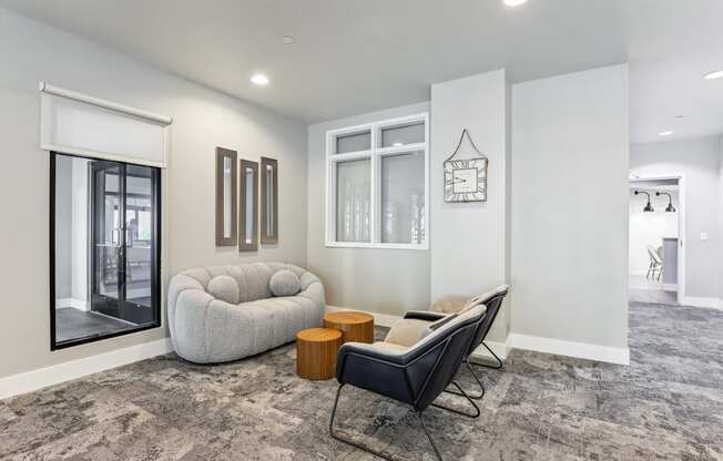 a lounge area with a white couch and chairs and a large window
