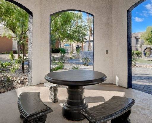 A table and two benches are in the foreground of a patio with arched openings.