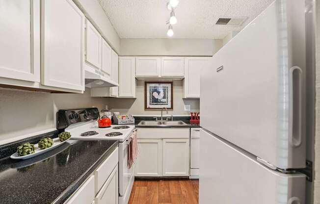 A kitchen with white cabinets and a fridge.