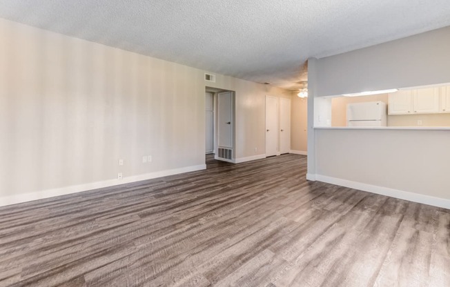 an empty living room with a kitchen in the background  at Redlands Park Apts, Redlands, CA