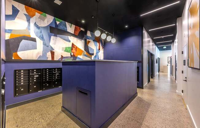 A hallway with a purple reception desk and a colorful mural on the wall.