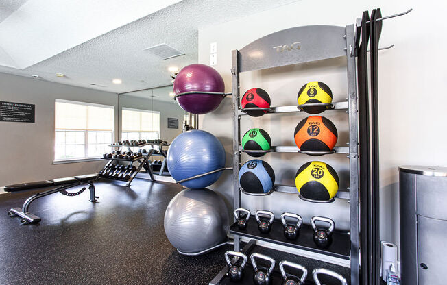 a gym with weights and balls on a rack