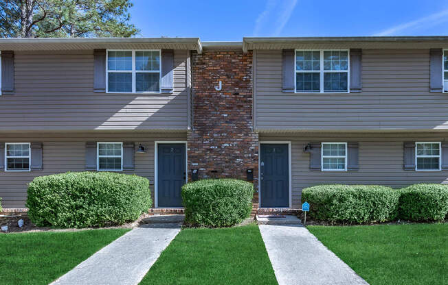 a house with a lawn in front of a brick building