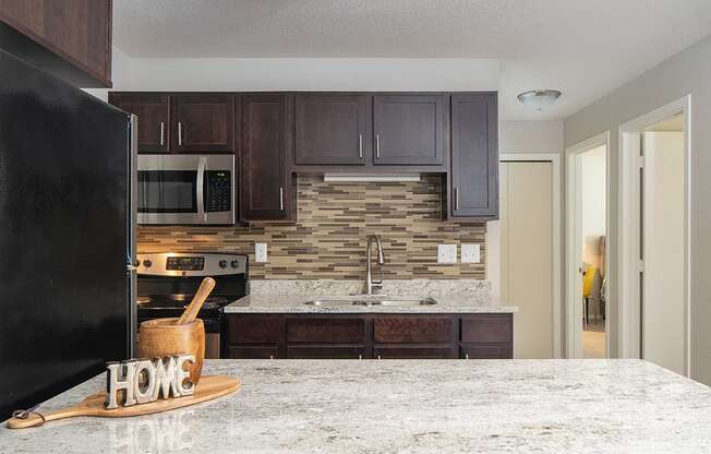 A kitchen with a black refrigerator and a marble countertop.at Prosper West, Waite Park, MN