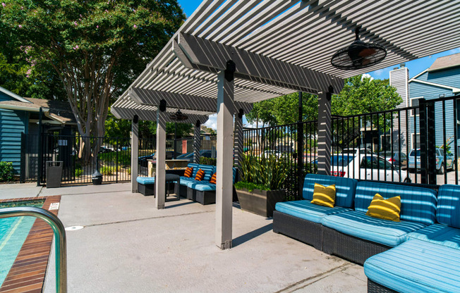 a patio with blue couches and umbrellas next to a pool