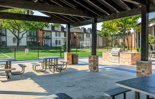 A park with tables and benches under a roof.