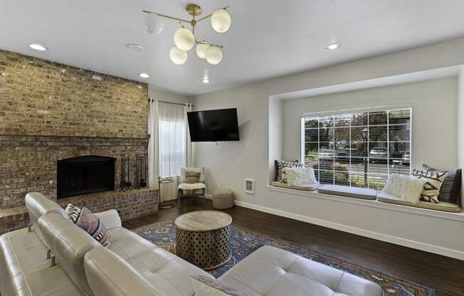 Spacious Living Room with a stone fireplace and river rock mantle with a large window at Serra Vista Apartment Homes, Lynnwood, 98087