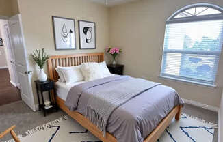 A bedroom with a bed, a chair, and a ceiling fan.