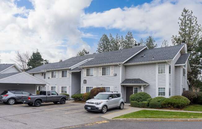 the view of an apartment building with cars parked in front of it